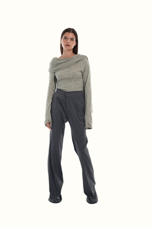 Woman wearing a gray sweater and gray tailored pants on a white background