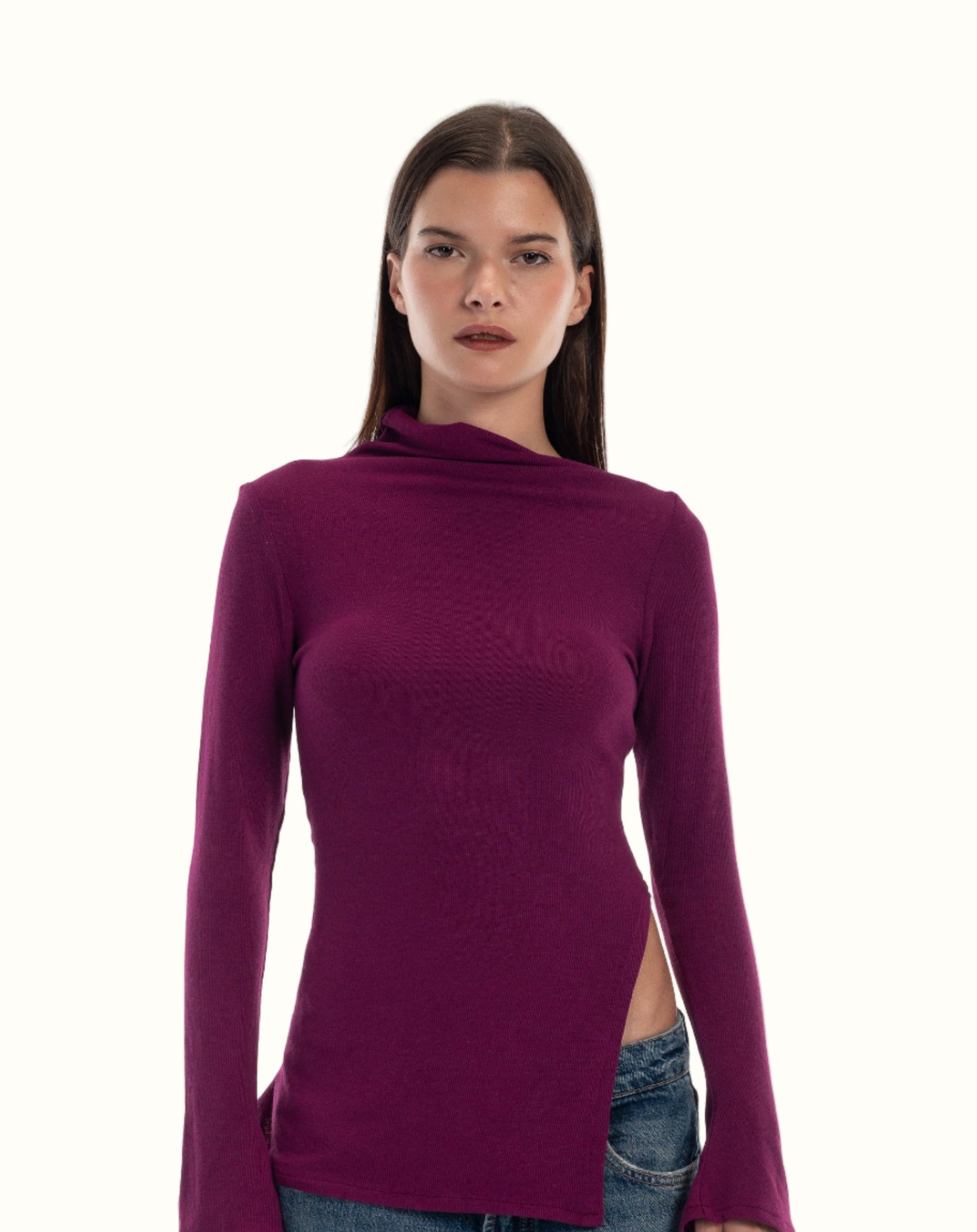 Woman wearing a purple long-sleeve top and blue jeans on a white background