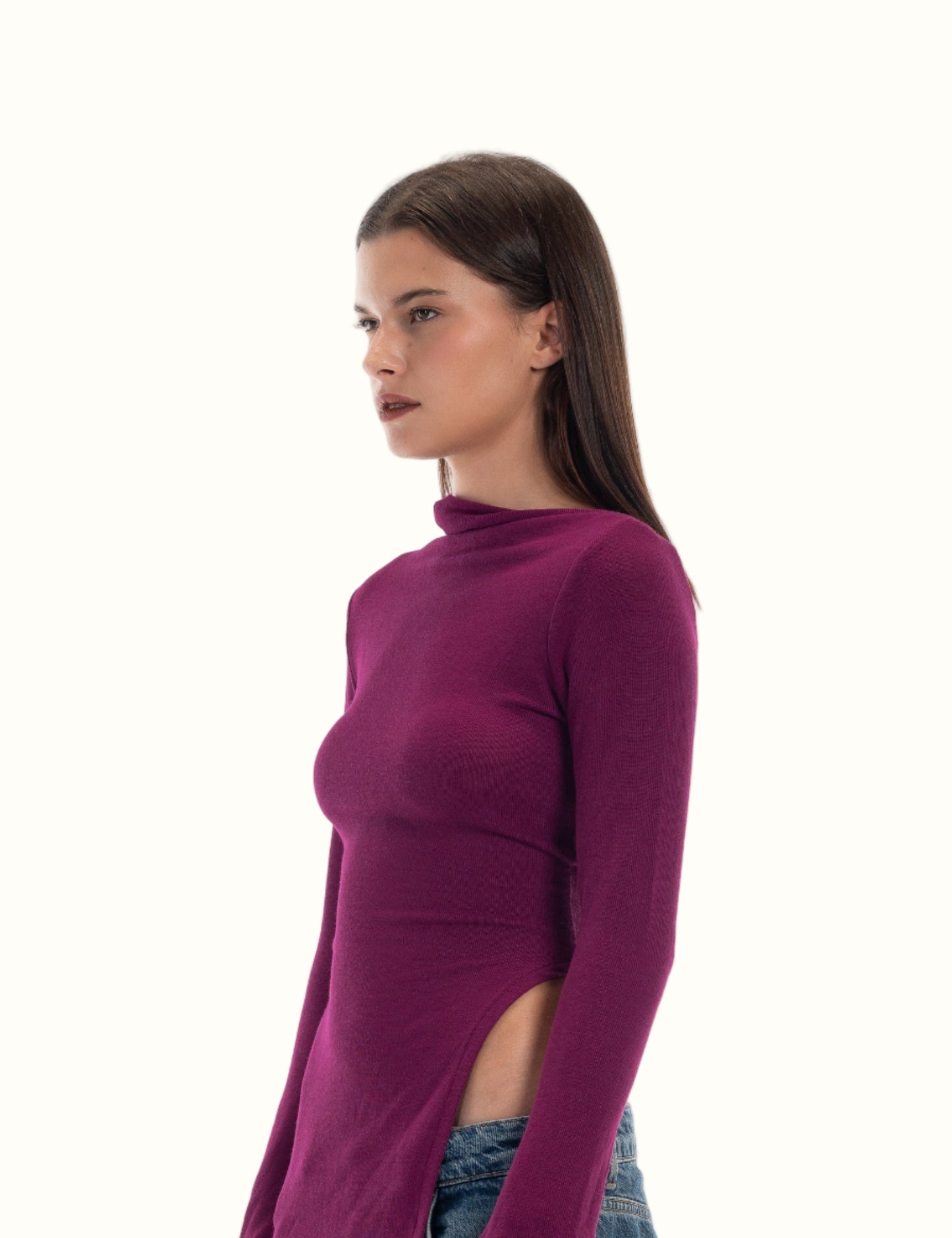Woman wearing a purple long-sleeve tturtleneck op and blue jeans on a white background. LUCE