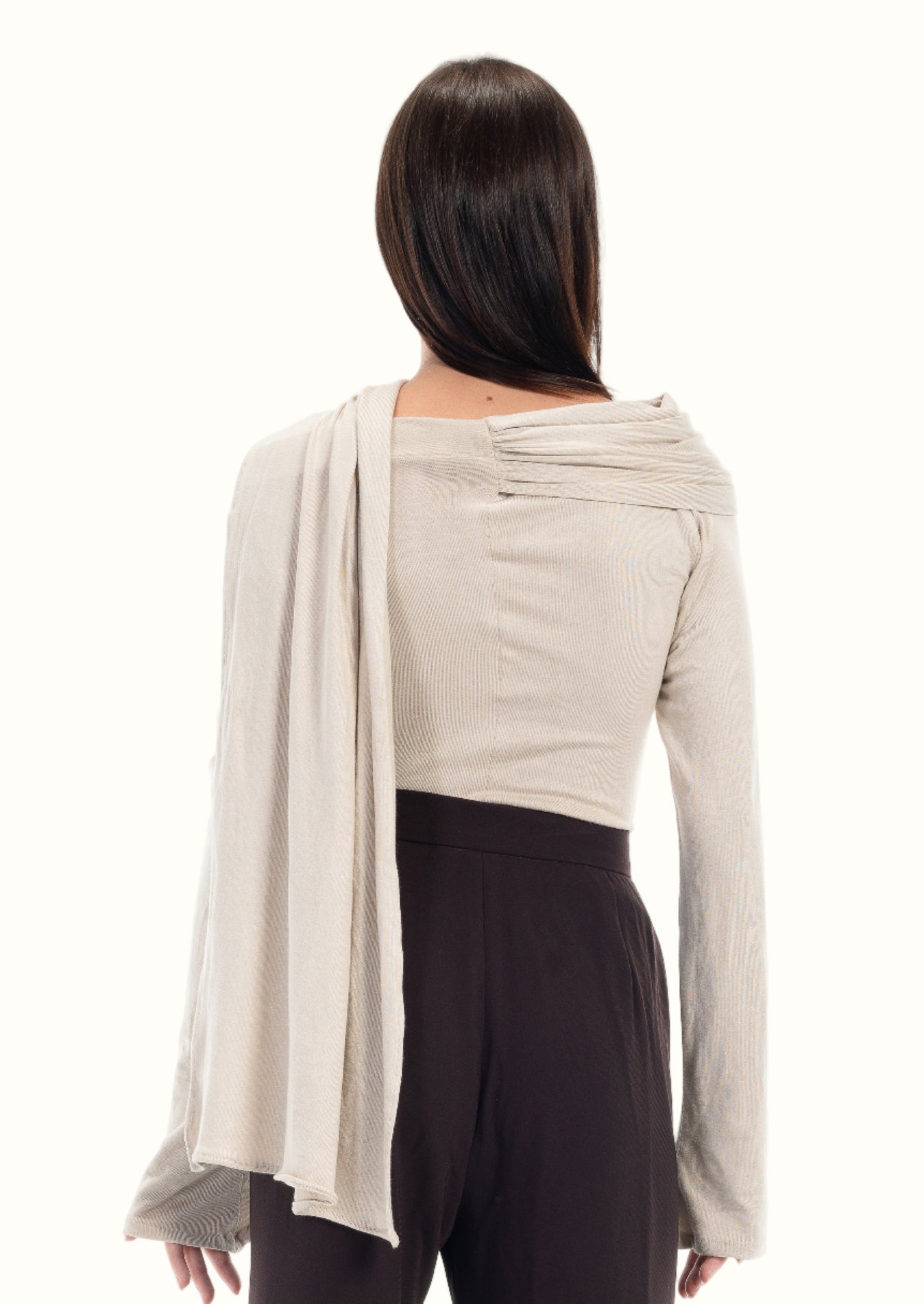Woman wearing a beige long-sleeve top and dark pants on a white background LUCE