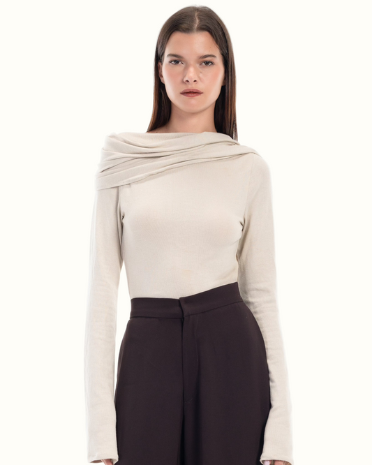 LUCE Woman wearing a beige long-sleeve cape top and dark brown pants on a white background