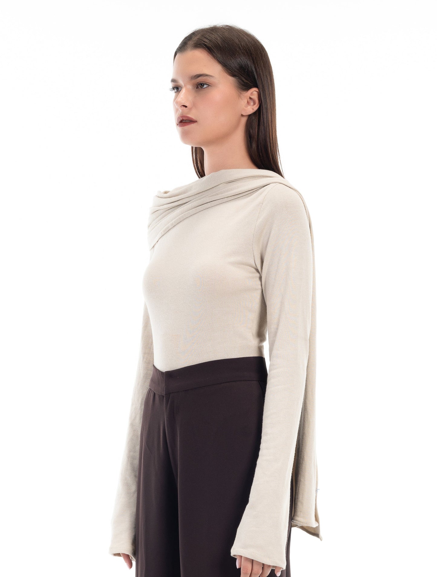 LUCE Woman wearing a beige long-sleeve topwith scarf detail and dark pants on a white background