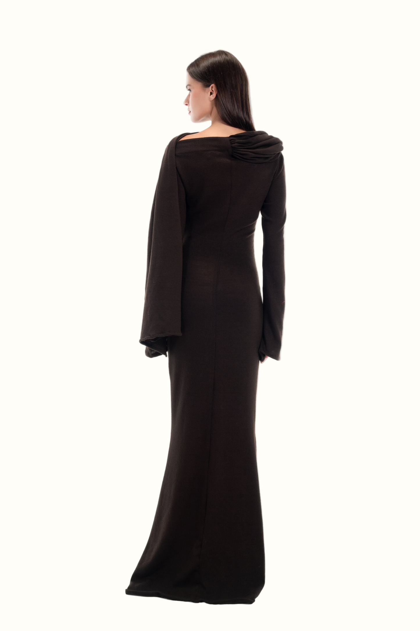 LUCE Woman wearing a long dark brown dress with a draped effect on a white background