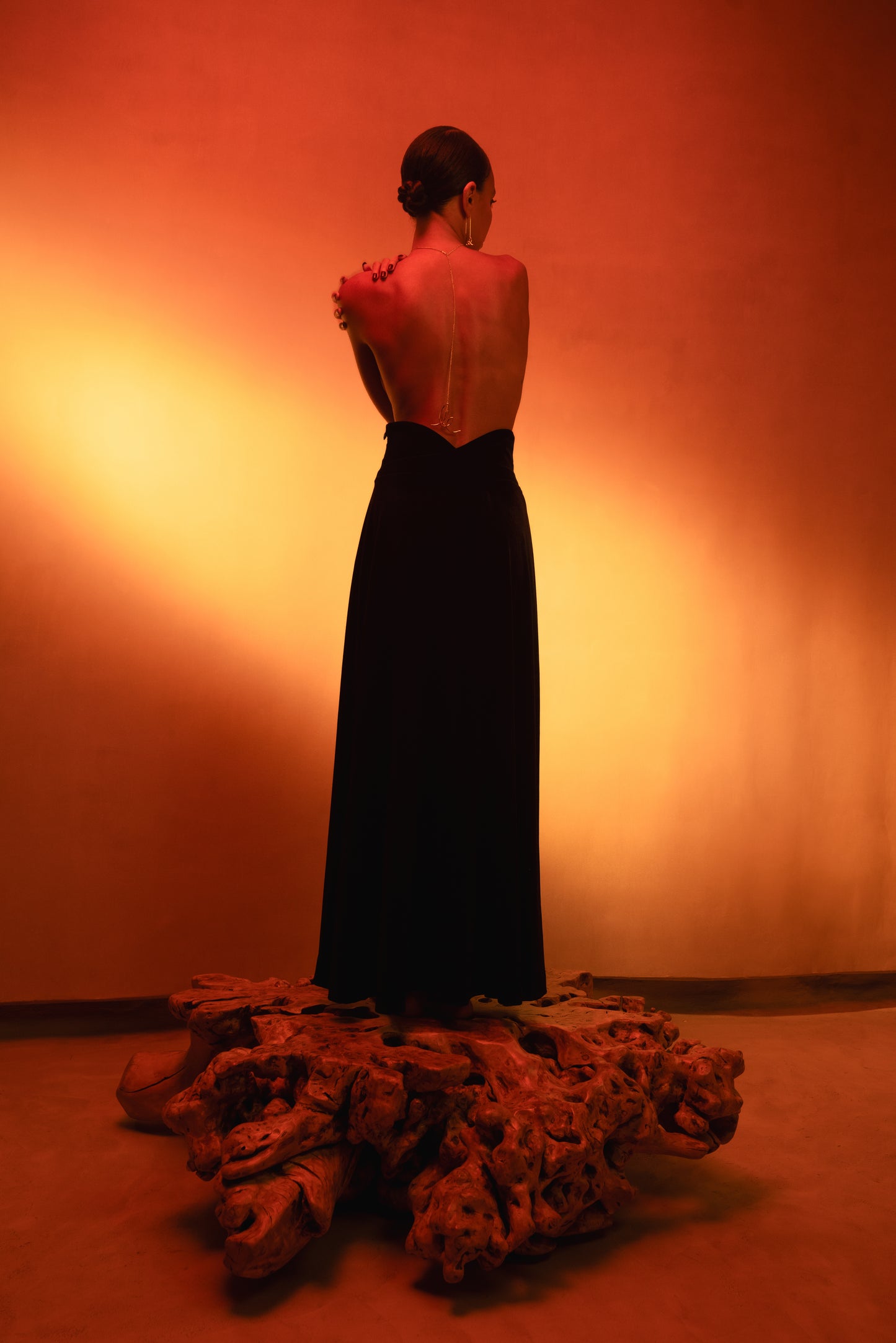 LUCE girl wearing a velvet maxi skirt with a logo chain on her open back