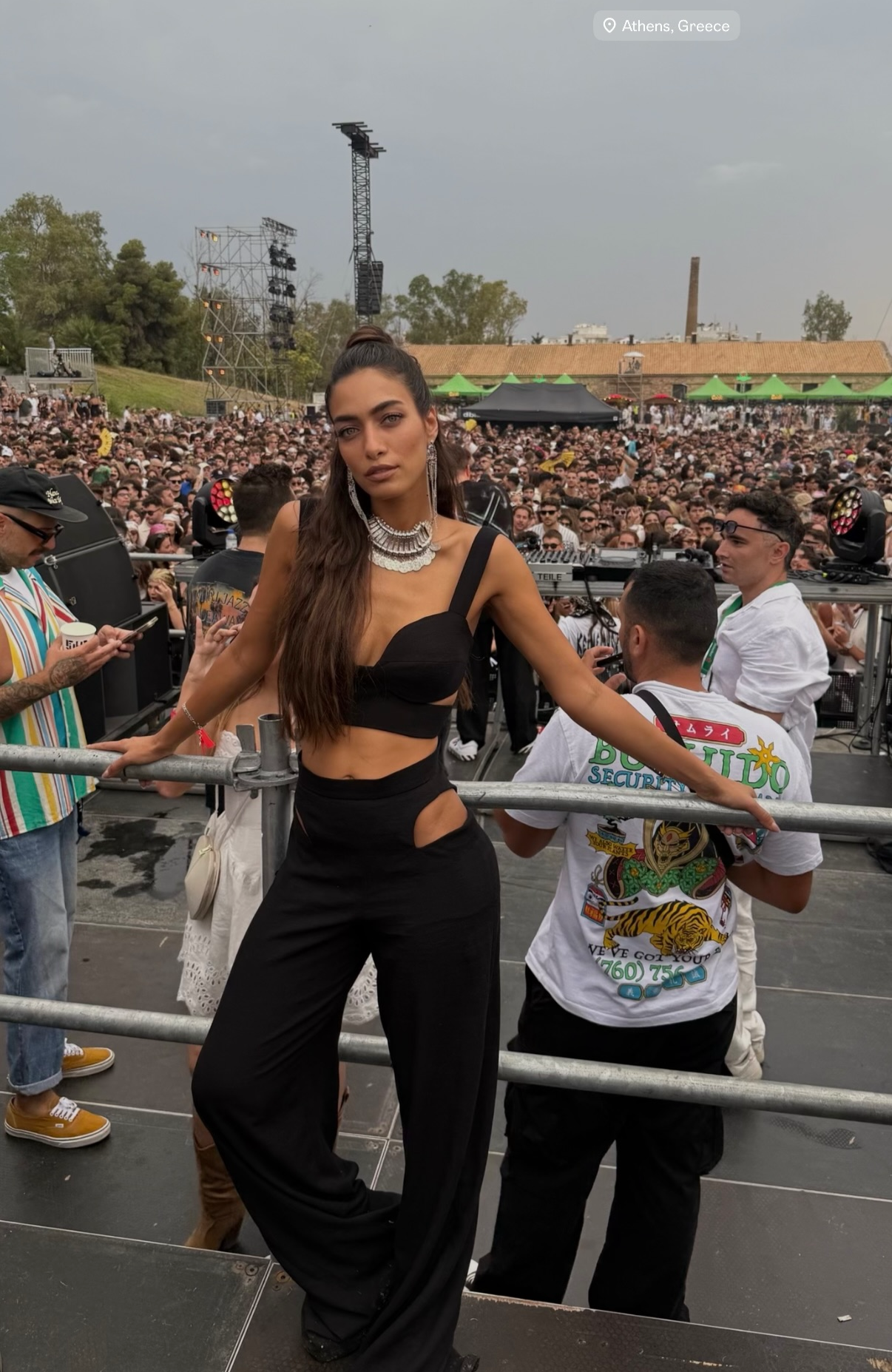 Woman posing in front of a crowd at an outdoor concert in athens, greece
