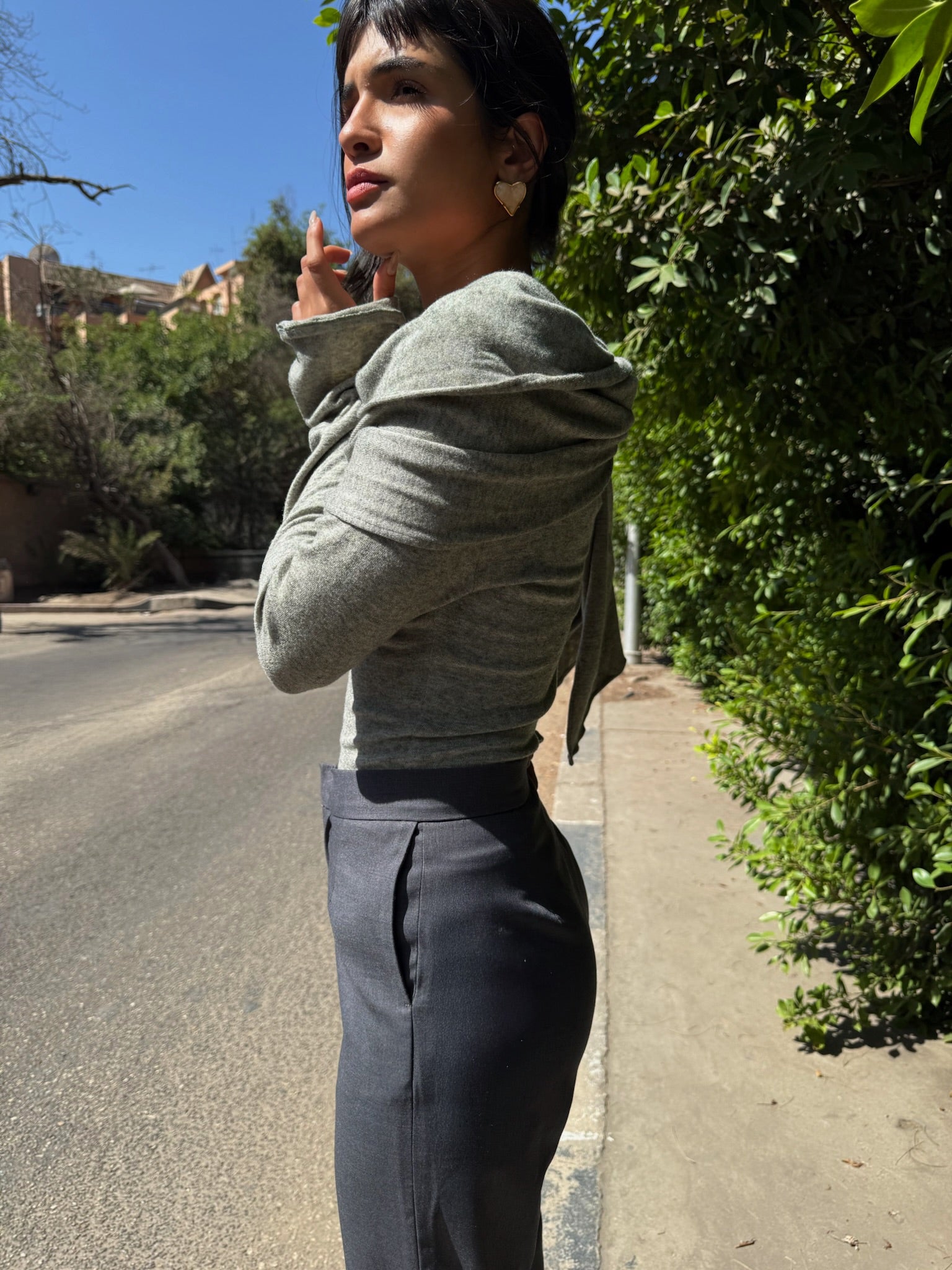 LUCE girl standing on a street with greenery in the background wearing full gray look