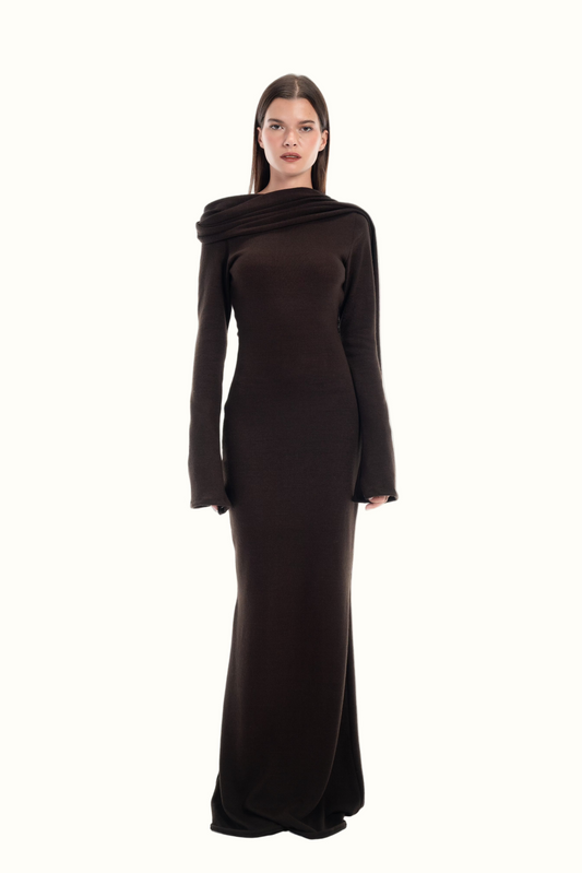 Woman wearing a maxi dark brown dress with a cowl neck with attached scarf detail on a white background